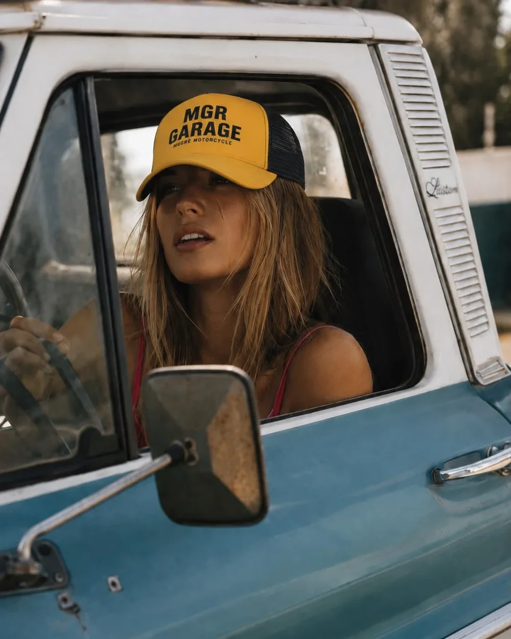 Chica con la gorra GARAGE YELLOW al volante de una pickup clásica